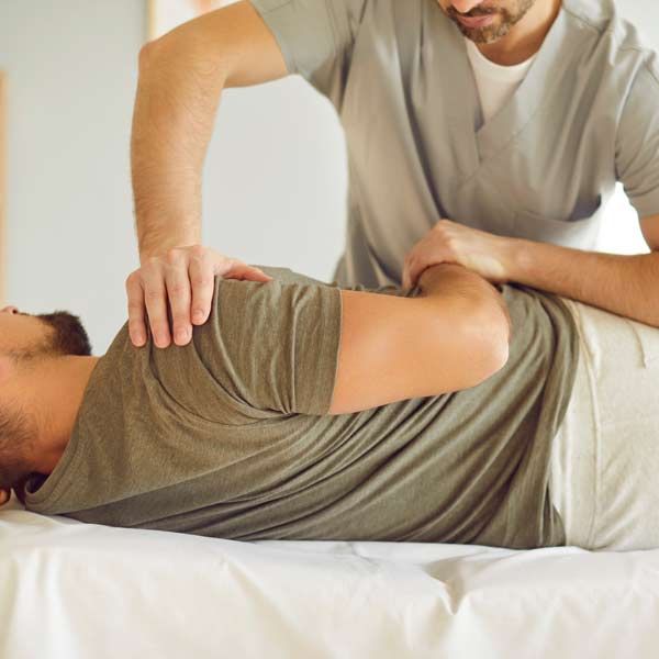 Chiropractor and Muscle Testing Practitioner gently stretching a patient on a treatment table in a bright clinic room