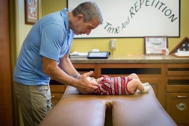 Chiropractor adjusting a patient on a treatment table in a clinic office
