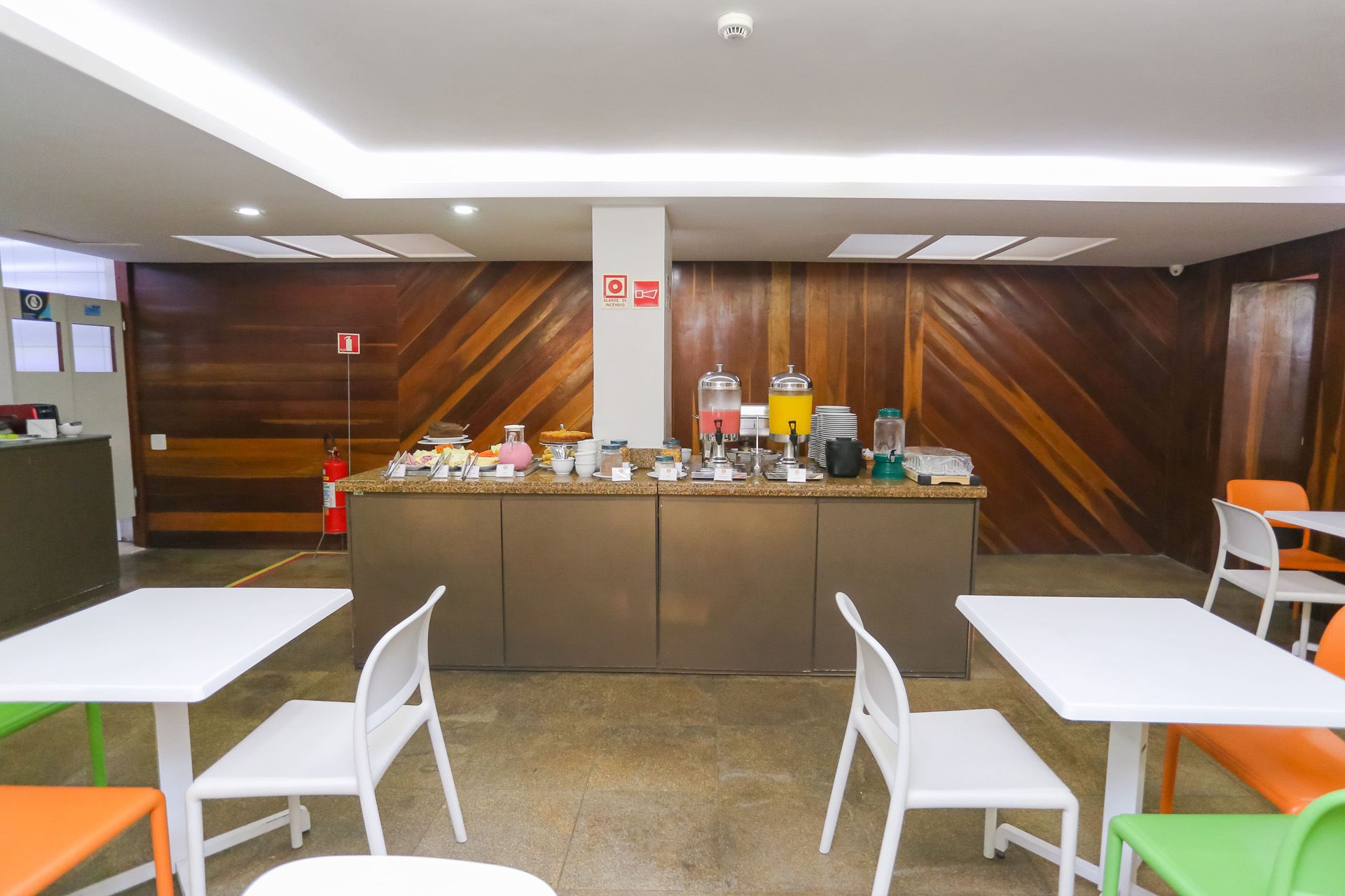 Mesa de café da manhã posta com ovos mexidos, bebidas e doces em um ambiente de restaurante.