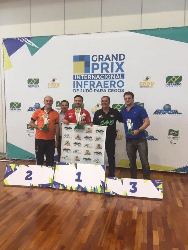Um grupo de homens em pé em um pódio em frente a uma placa que diz grande prêmio