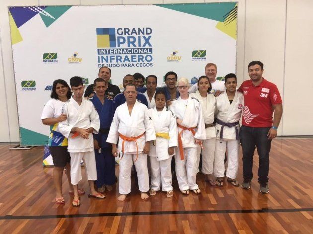 Um grupo de pessoas em pé na frente de uma placa que diz grande prêmio