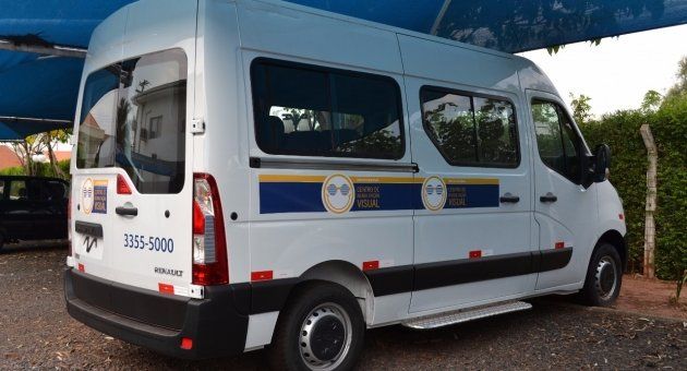 Uma van branca está estacionada sob um guarda-chuva azul.