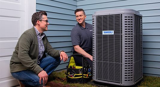 Man consulting with HVAC technician next to an air conditioning unit outside a house.