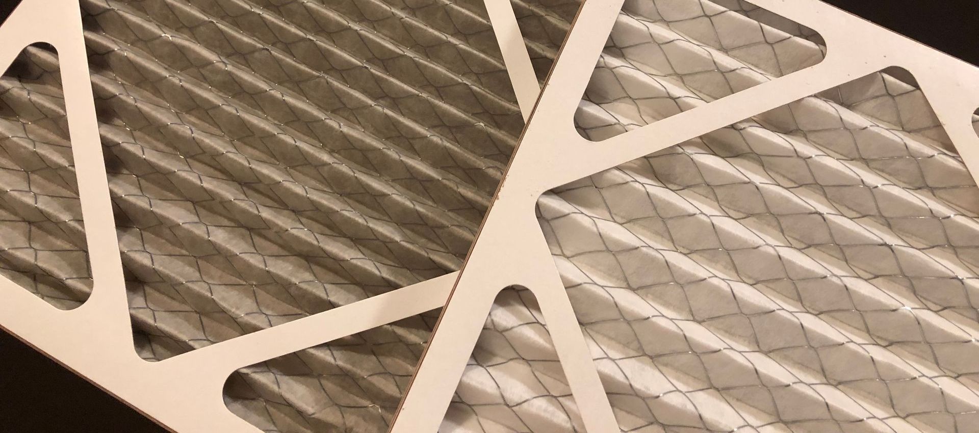 Air filter, one clean, one dirty. Both have white frame, pleated, and diamond cross-section.