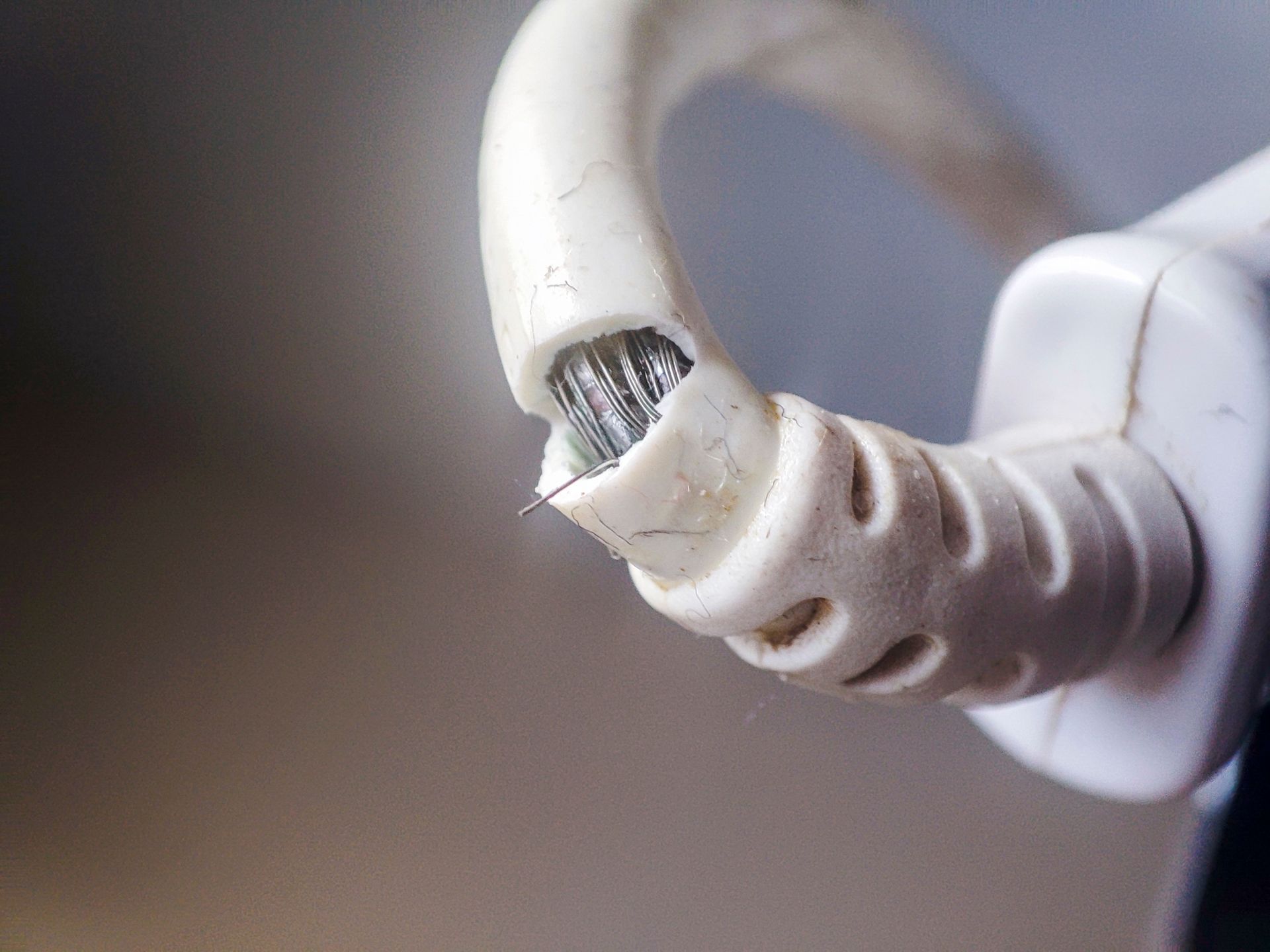A close up of a broken cord coming out of a plug.