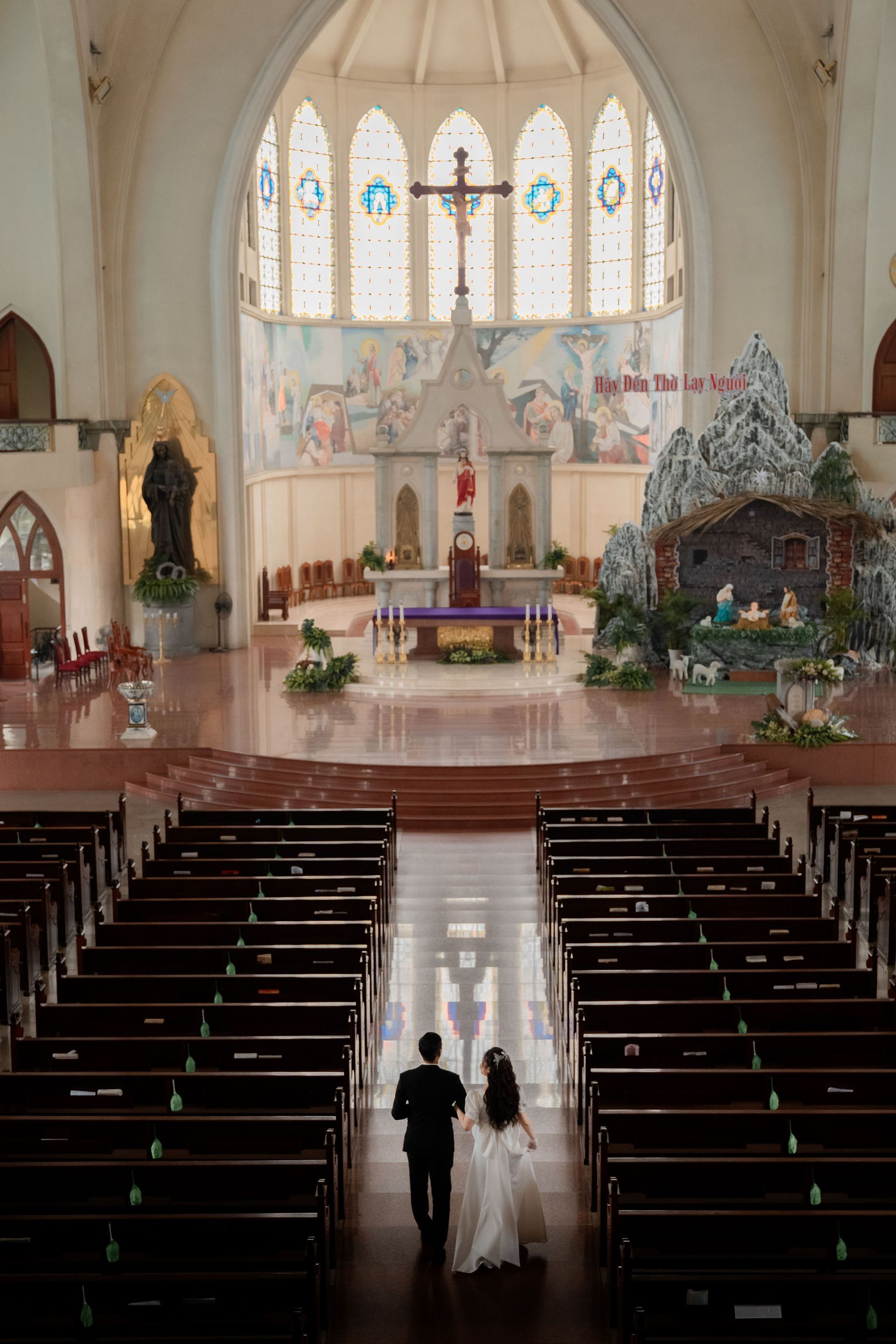 Bride and groom walking down the aisle in a bright church, with pews and an altar ahead