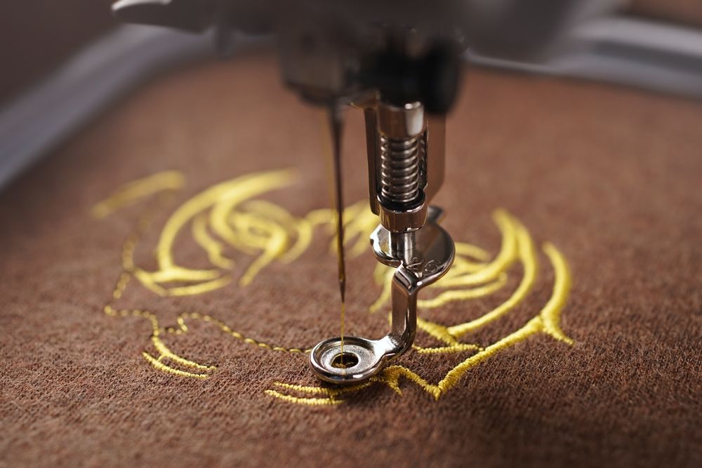 A close up of a sewing machine embroidery a design on a piece of fabric.