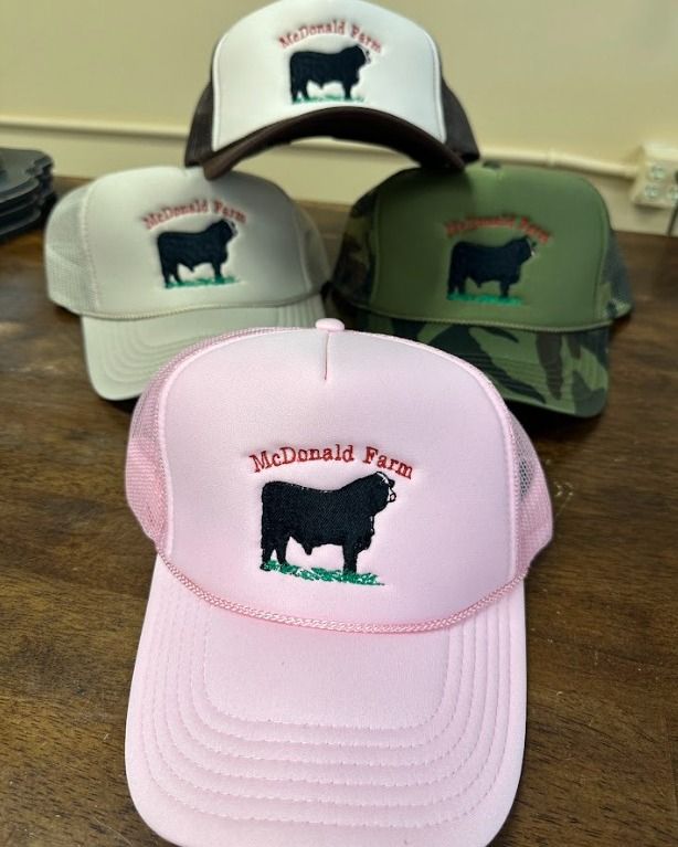 Four hats are sitting on a table and one of them says mcdonald farm.