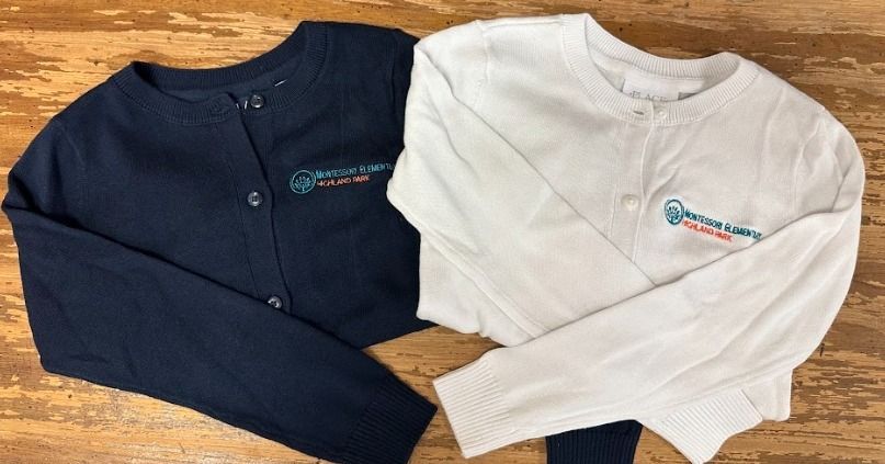 Two sweaters, one blue and one white, are sitting on a wooden table.