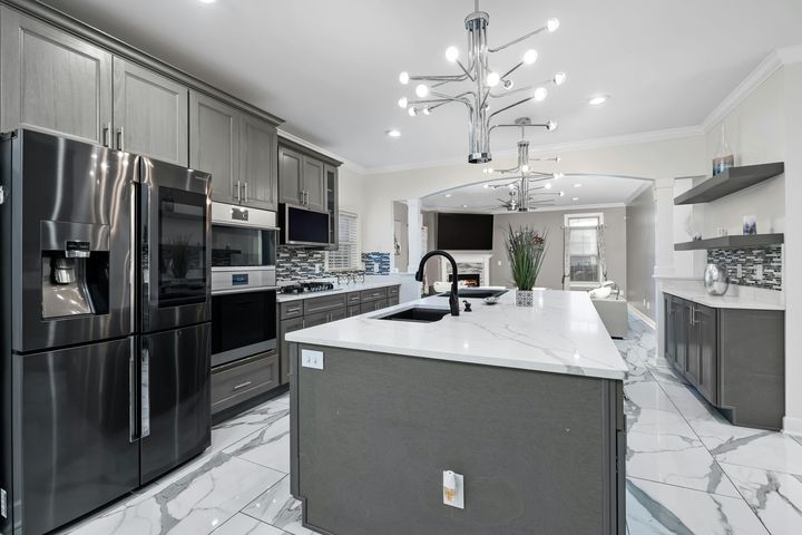 Modern kitchen with stainless steel appliances, gray cabinets, and a large white island
