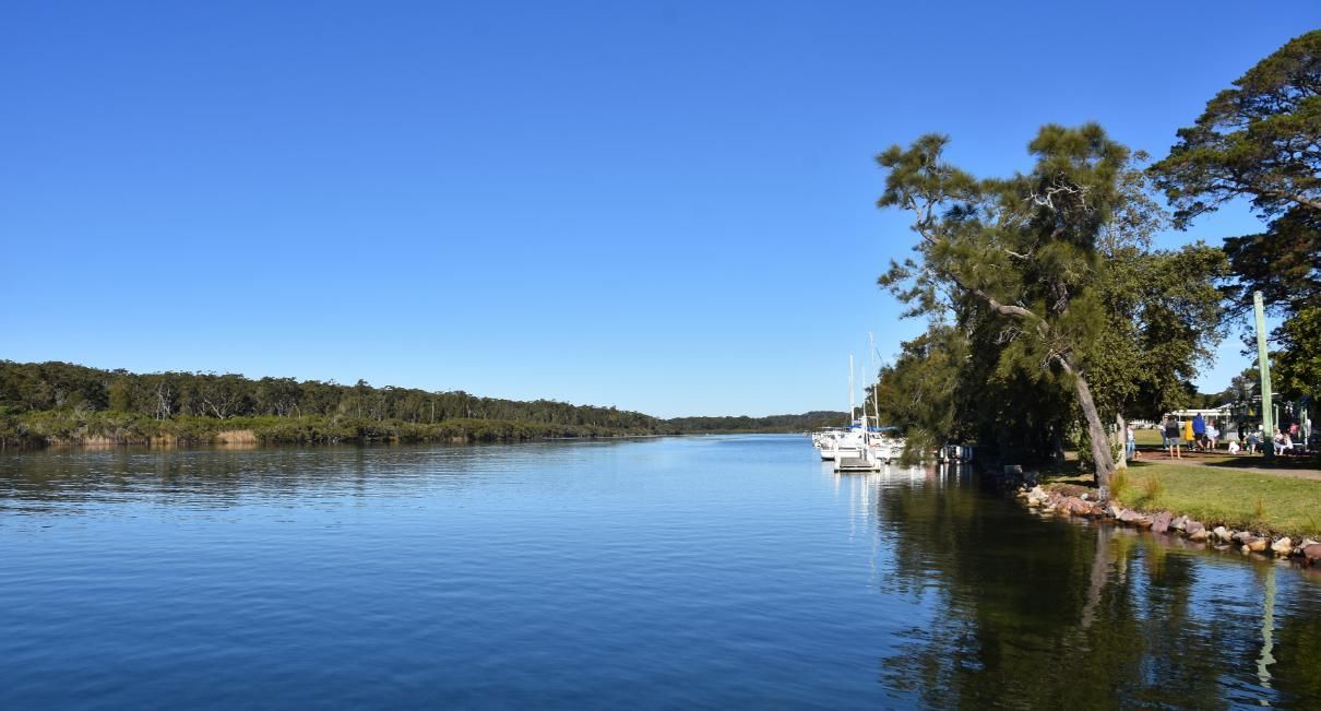 A Large Body of Water Surrounded by Trees on a Sunny Day — Bonanno's Menswear in Shellharbour, NSW