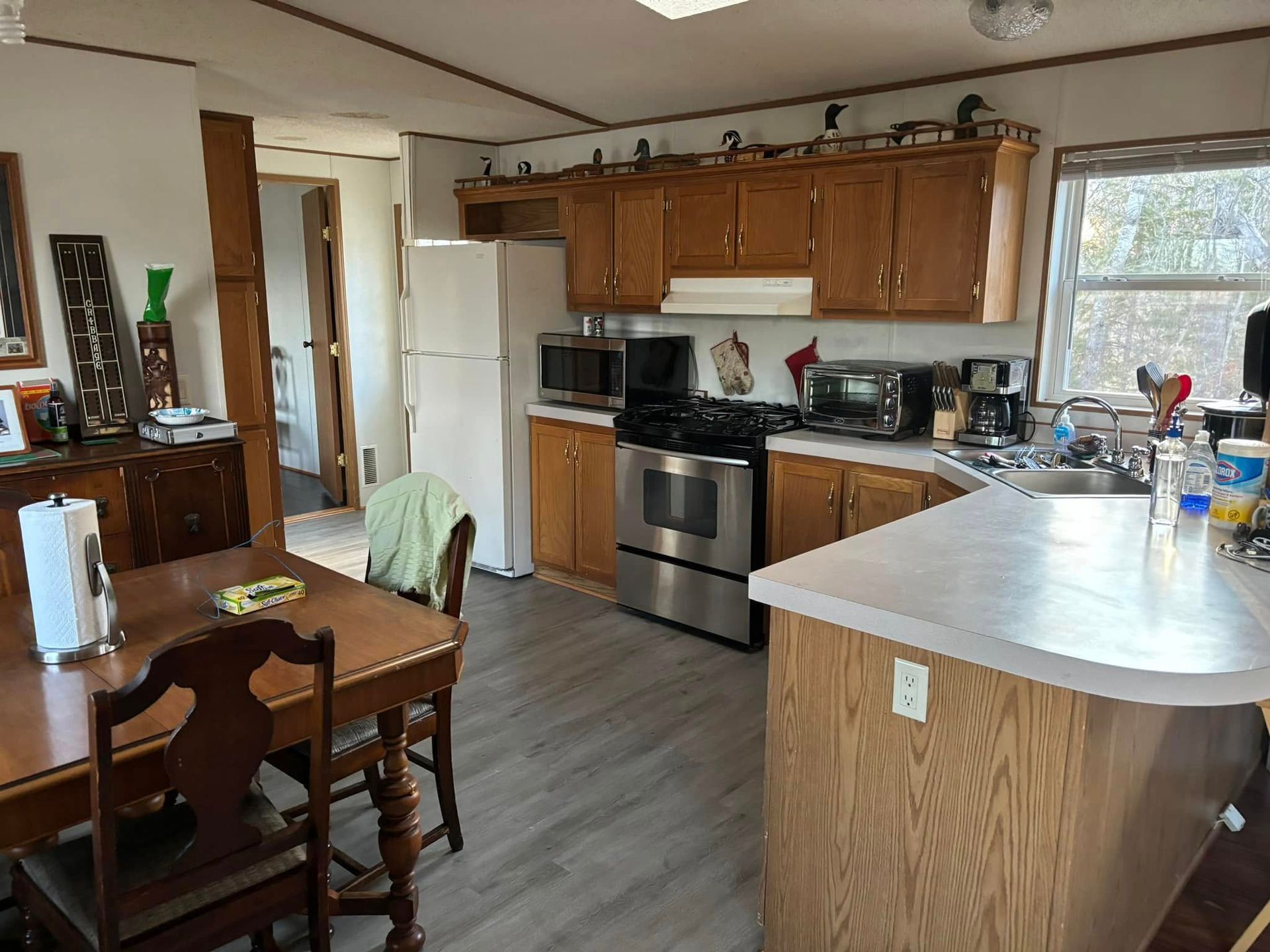 A kitchen with oak cabinets, stainless steel appliances, a white refrigerator, and a wooden dining table in the foreground.