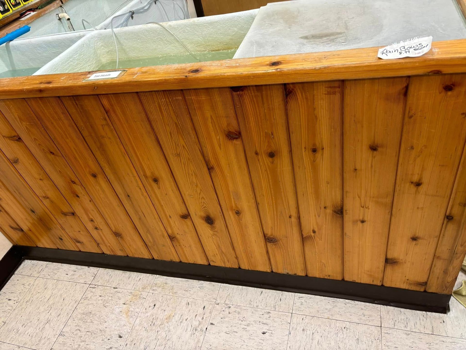 A wooden-paneled display base with a top shelf holding a clear water tank, viewed from a high angle.