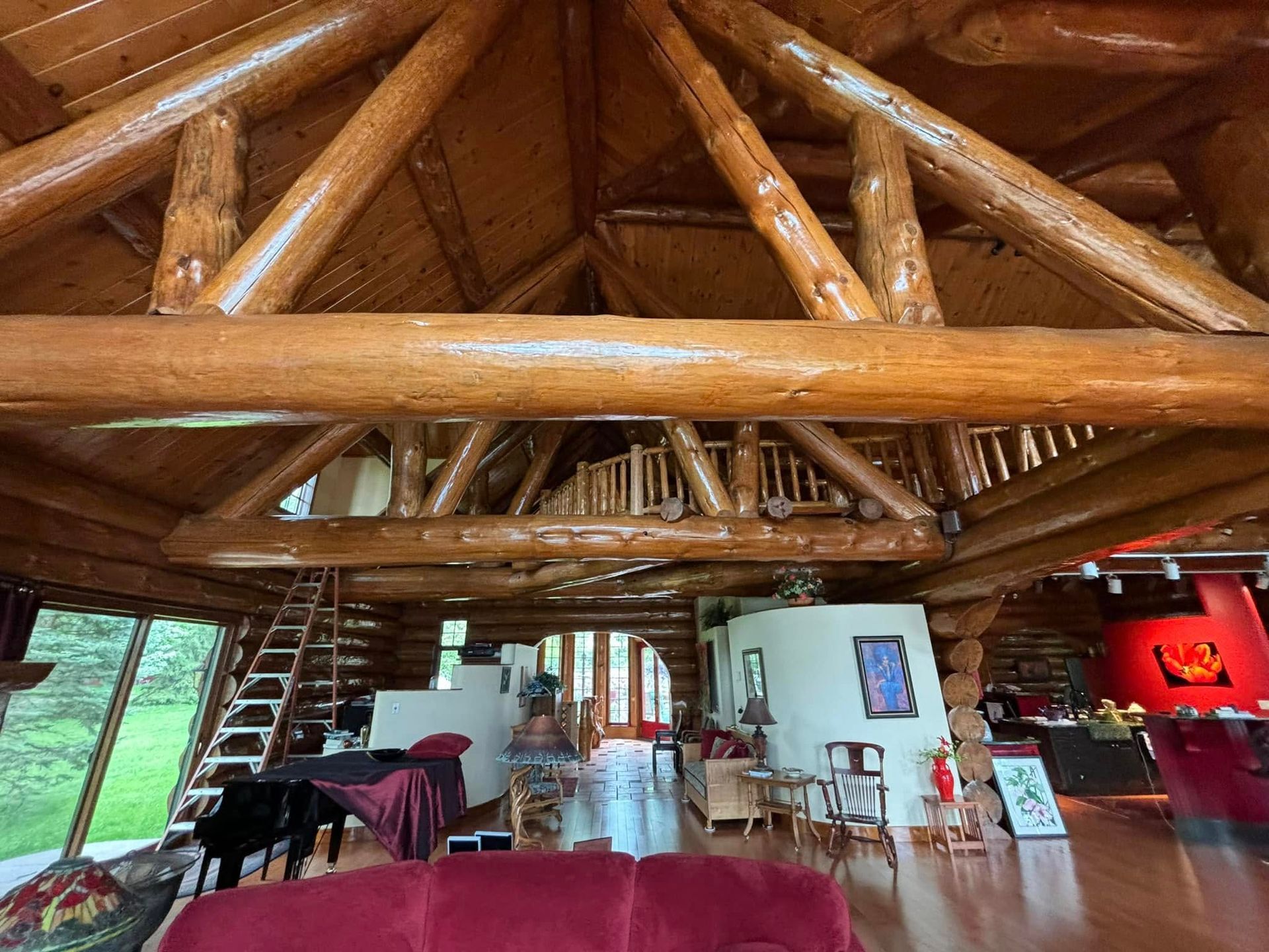 Spacious log cabin interior with high vaulted timber ceilings, exposed beams, a loft, and a cozy furnished living area.