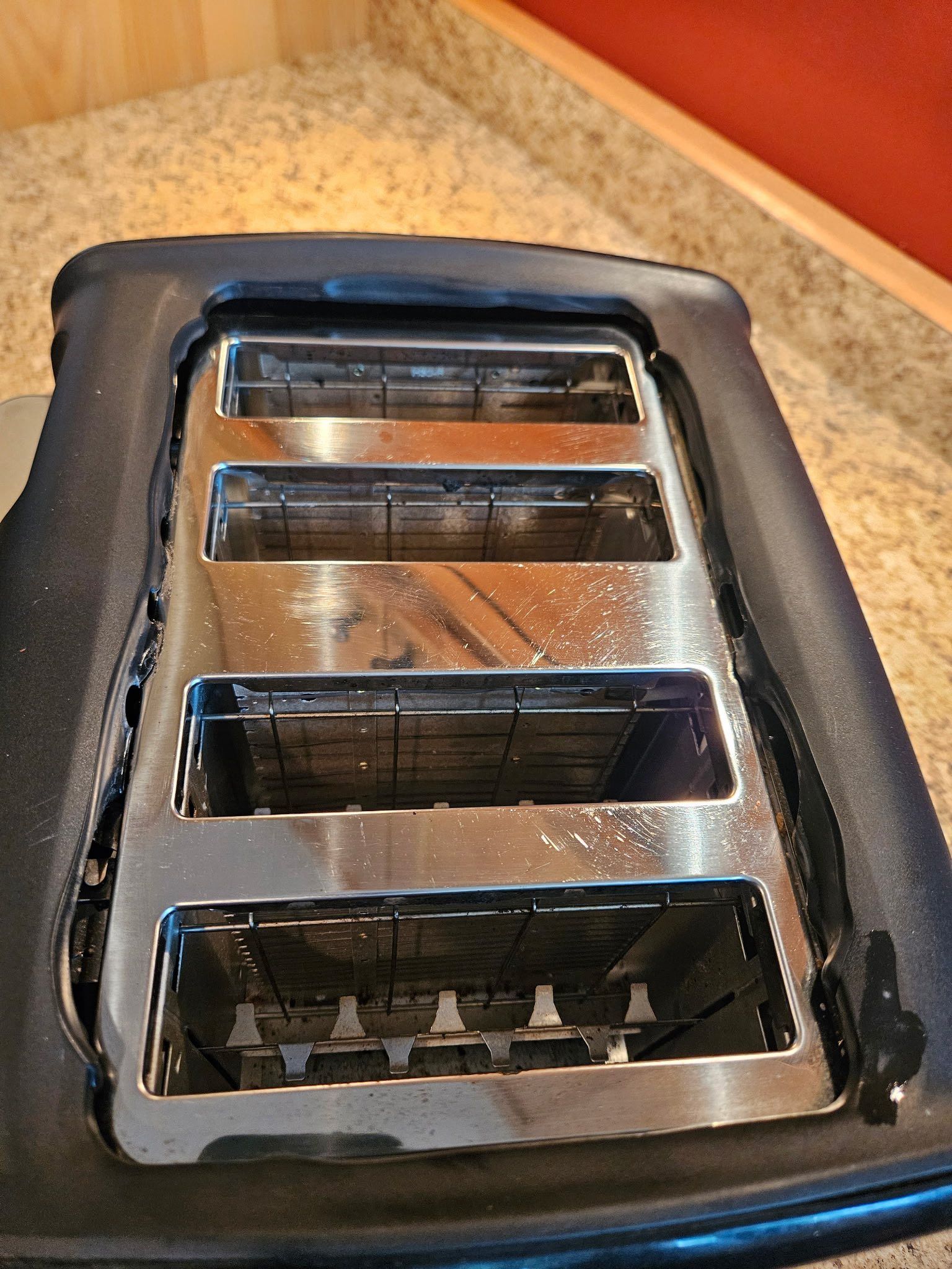 A top-down view of a four-slice toaster with a metallic top and black housing on a countertop.