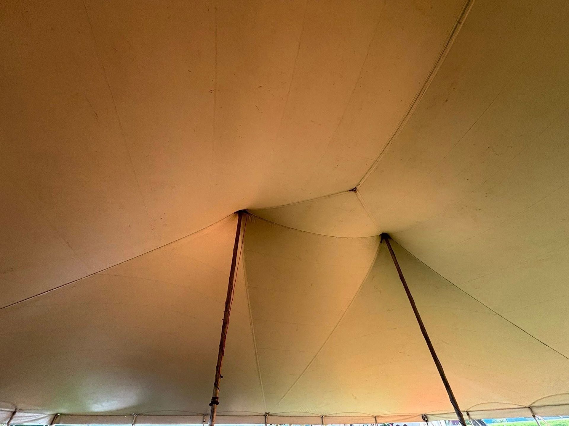 Interior view of a light-colored canvas tent roof supported by two vertical poles.