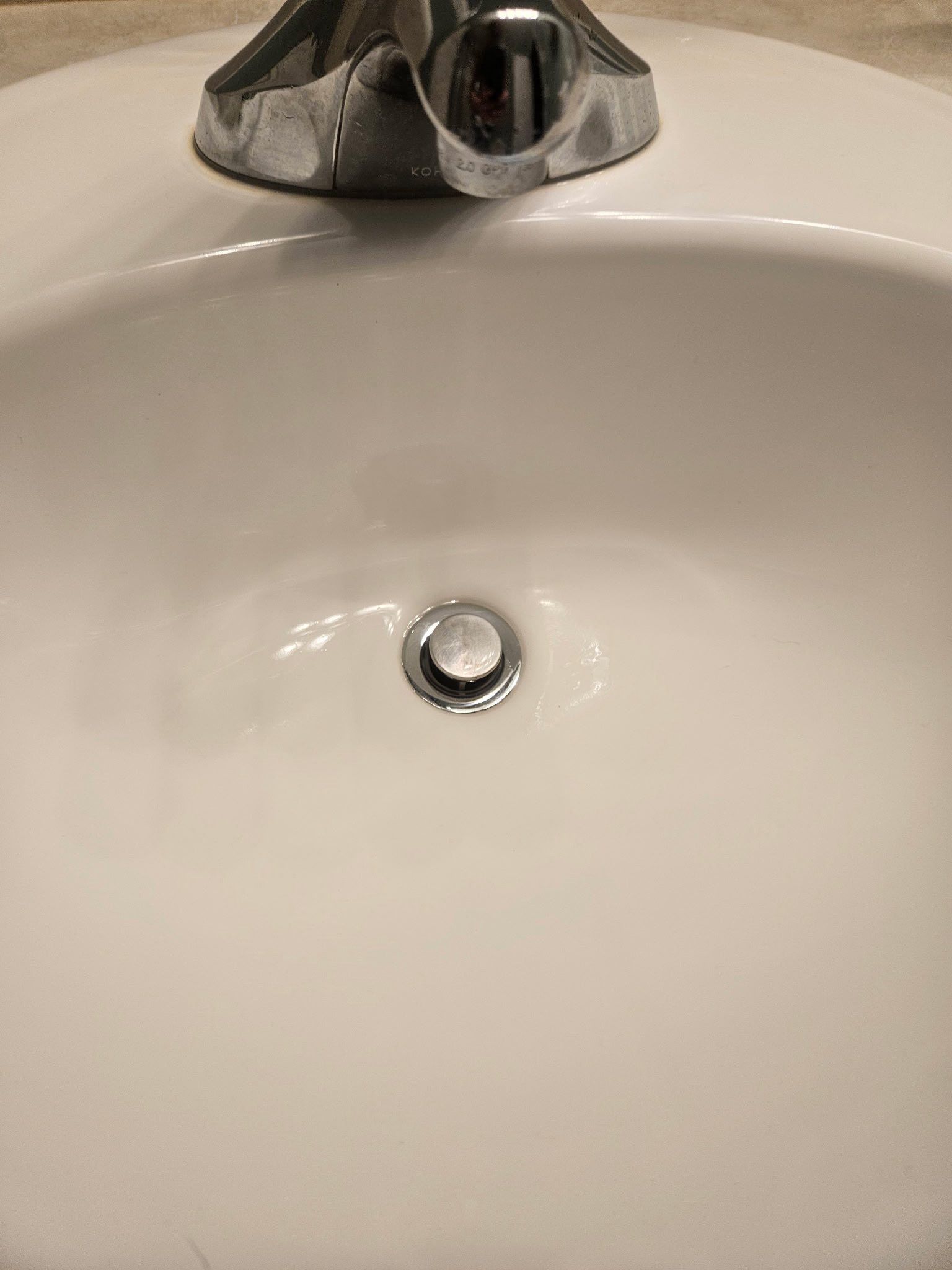 A white ceramic bathroom sink with a polished chrome faucet and a closed drain stopper.