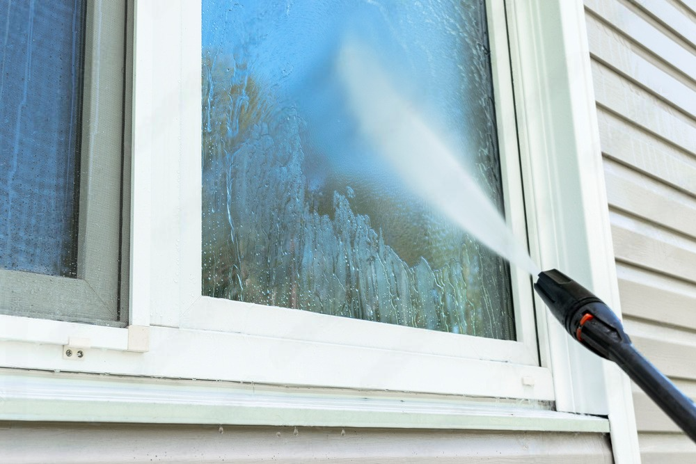 A close up of a high pressure washer spraying water on a concrete surface.