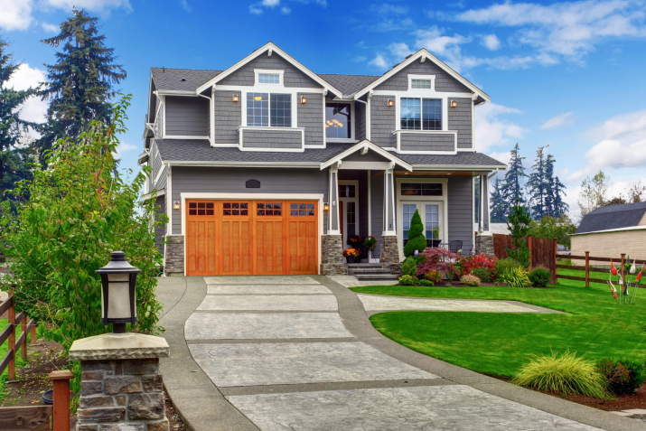 A large house with a wooden garage door and a driveway leading to it.