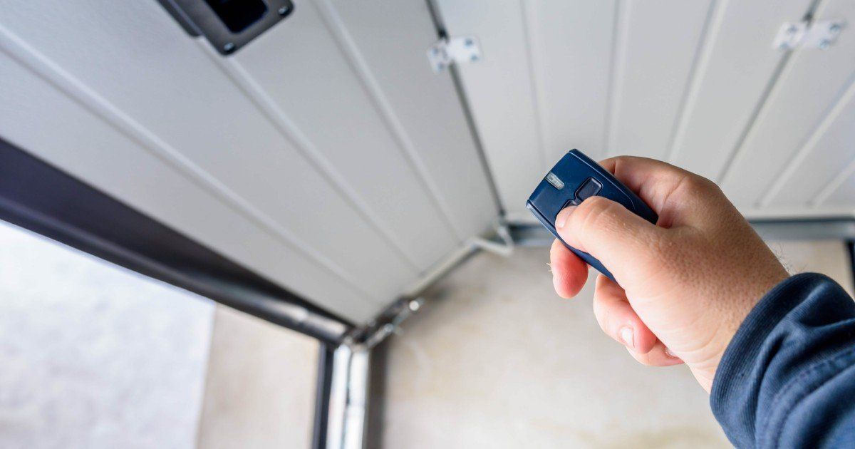 Hand-holding a remote control to operate a garage door opener, emphasizing ease of use and modern convenience.