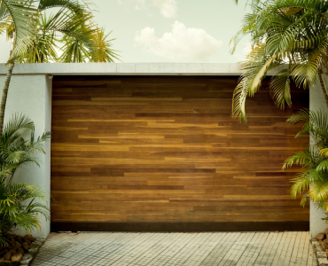 A wooden garage door is surrounded by palm trees.