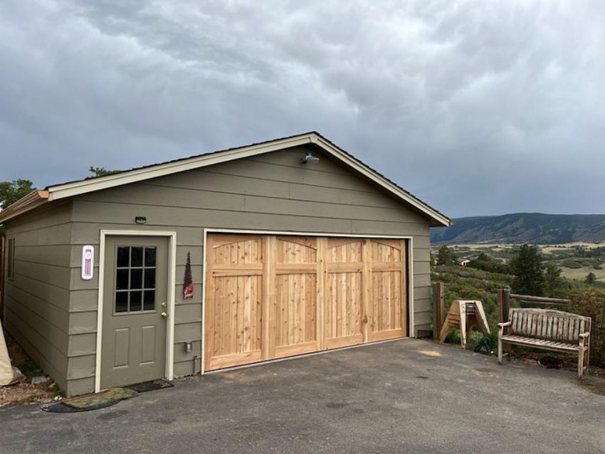 Detached garage with natural wood doors showcasing garage door styles for homes in Colorado Springs.