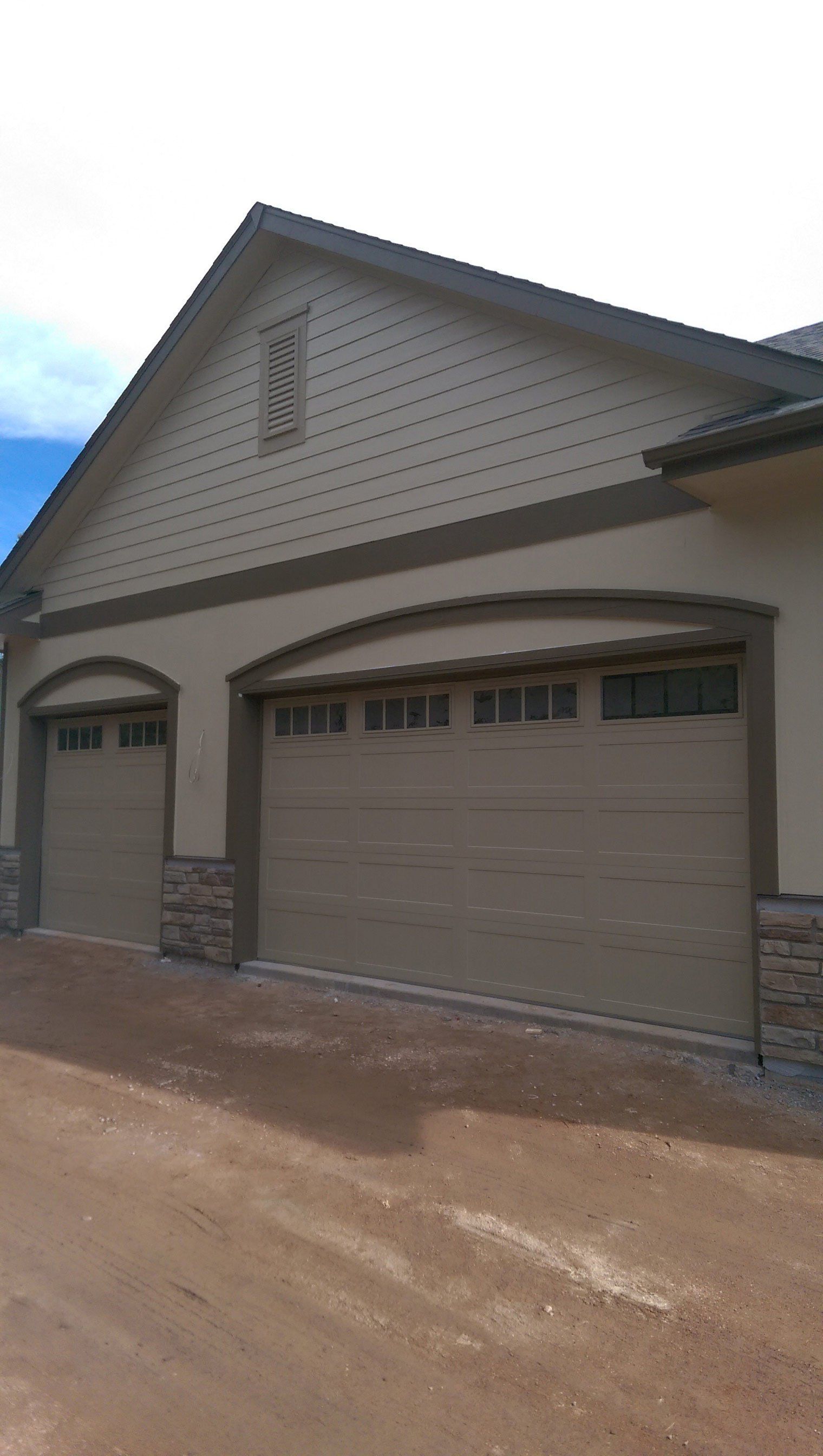 There are two garage doors on the side of a house.