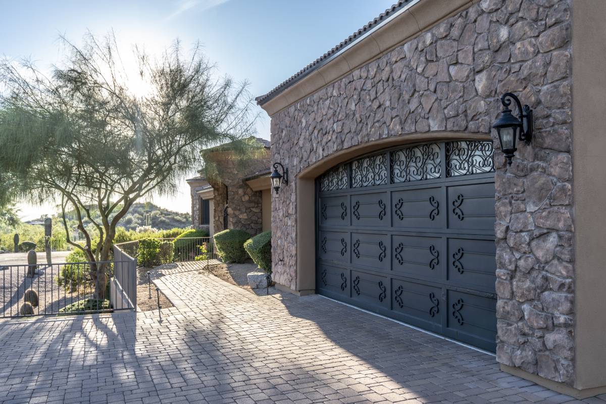 A large black garage door is sitting in front of a stone building.