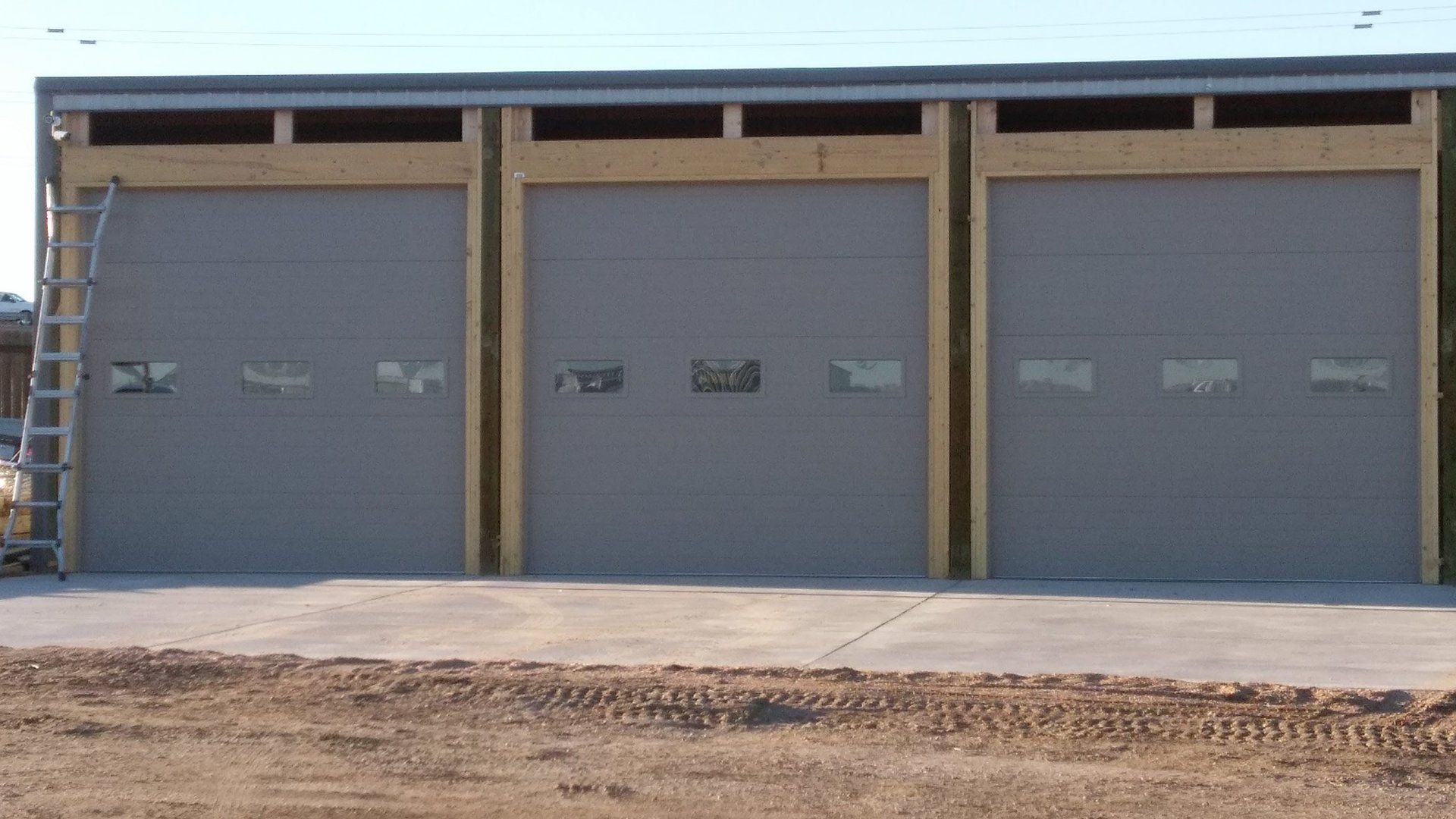 A row of garage doors with a ladder in front of them