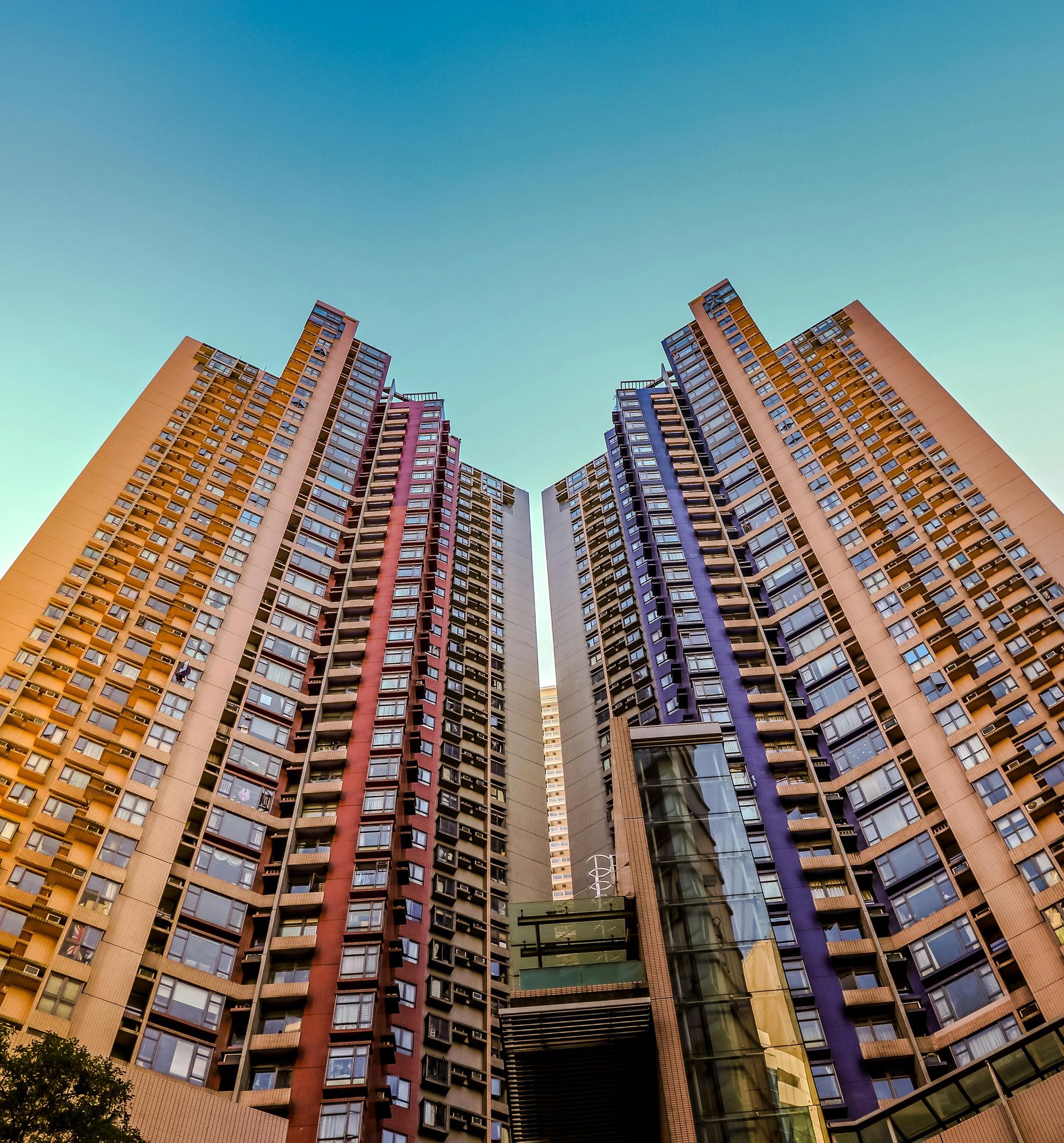 Two tall residential buildings with colorful balconies against a blue sky.