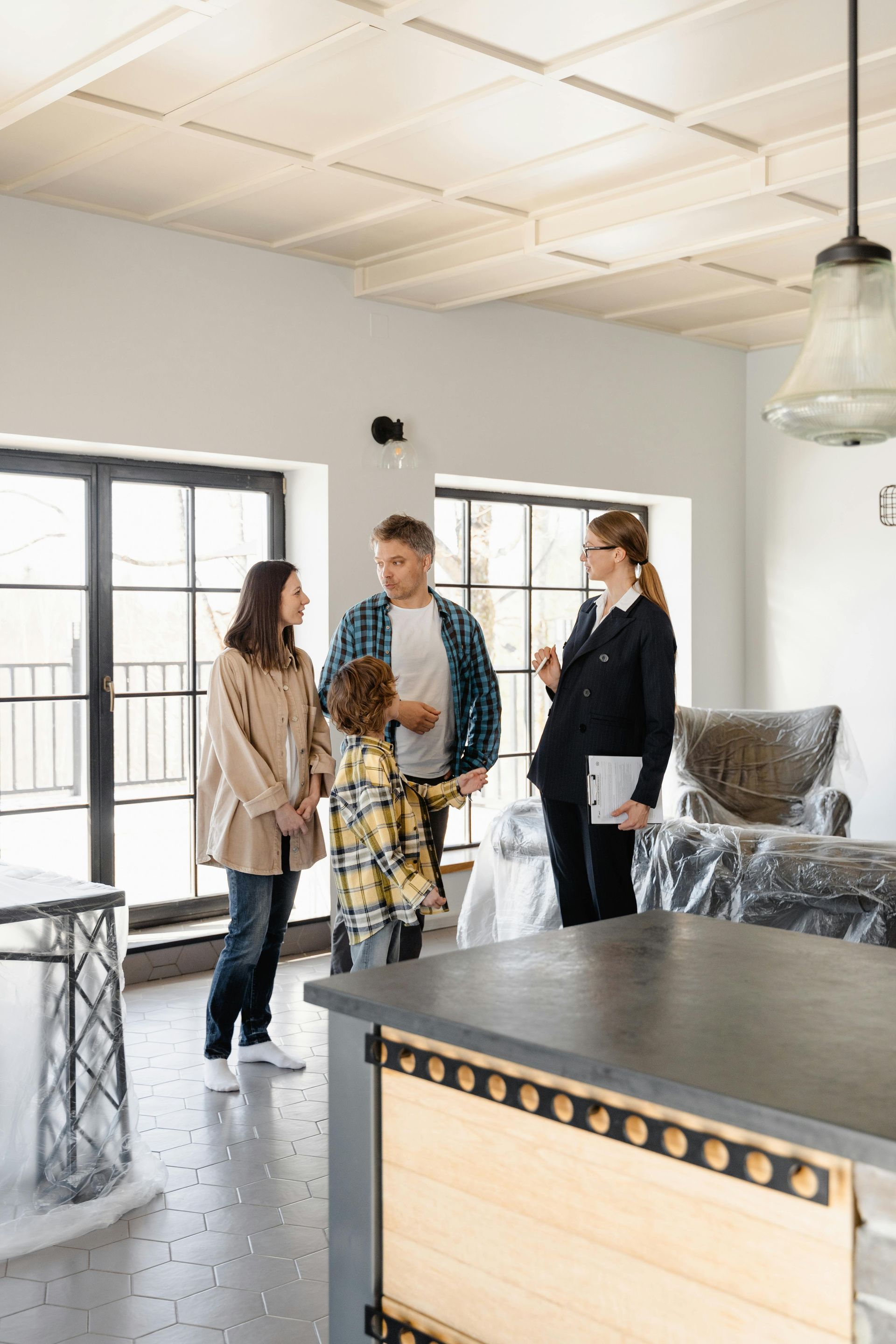 Family with a realtor viewing an unfinished home, discussing details.