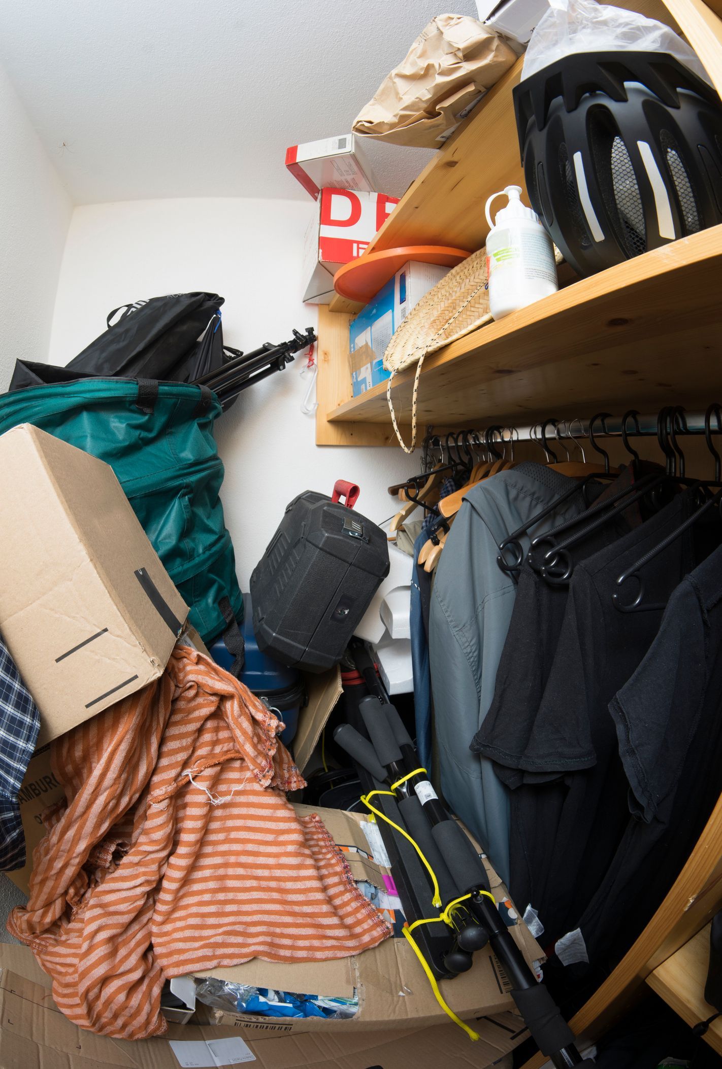 A closet filled with clothes , boxes , and other items.