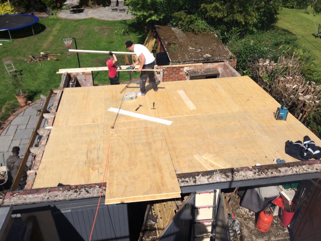 A picture of a ceiling joists being covered with plywood by Roofers Manchester
