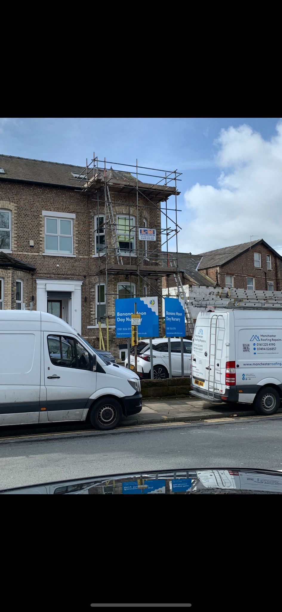 A white van is parked in front of a building under construction.
