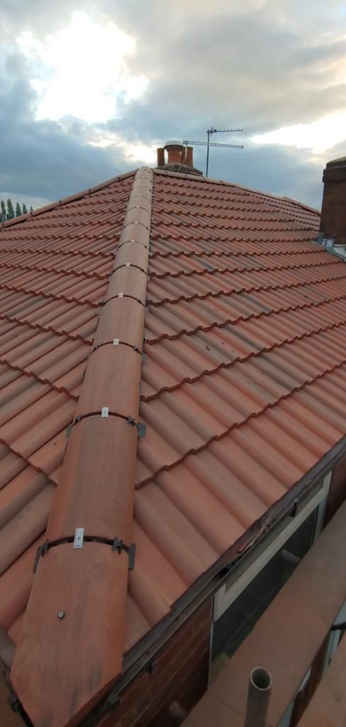 A close up of a tiled roof with a chimney on top of it.