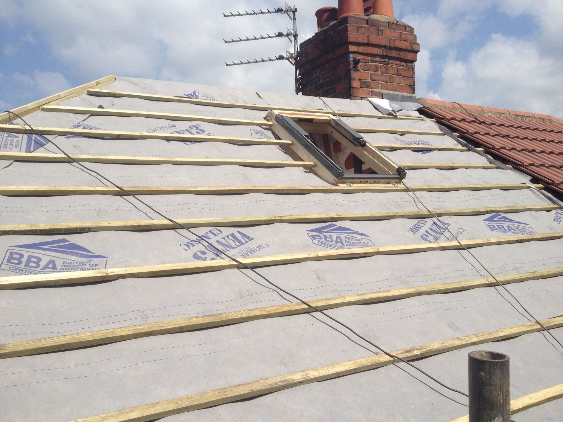 A roof with a window and a chimney on it
