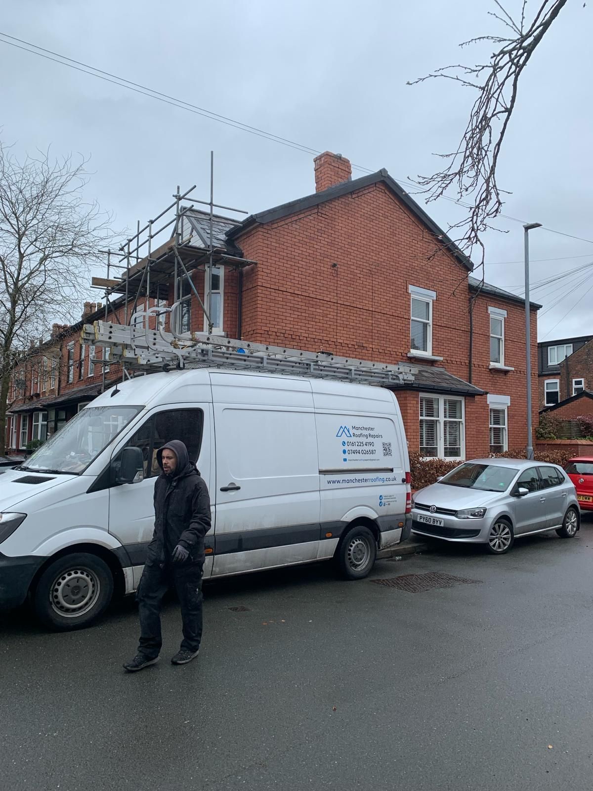 A white van is parked in front of a brick building.