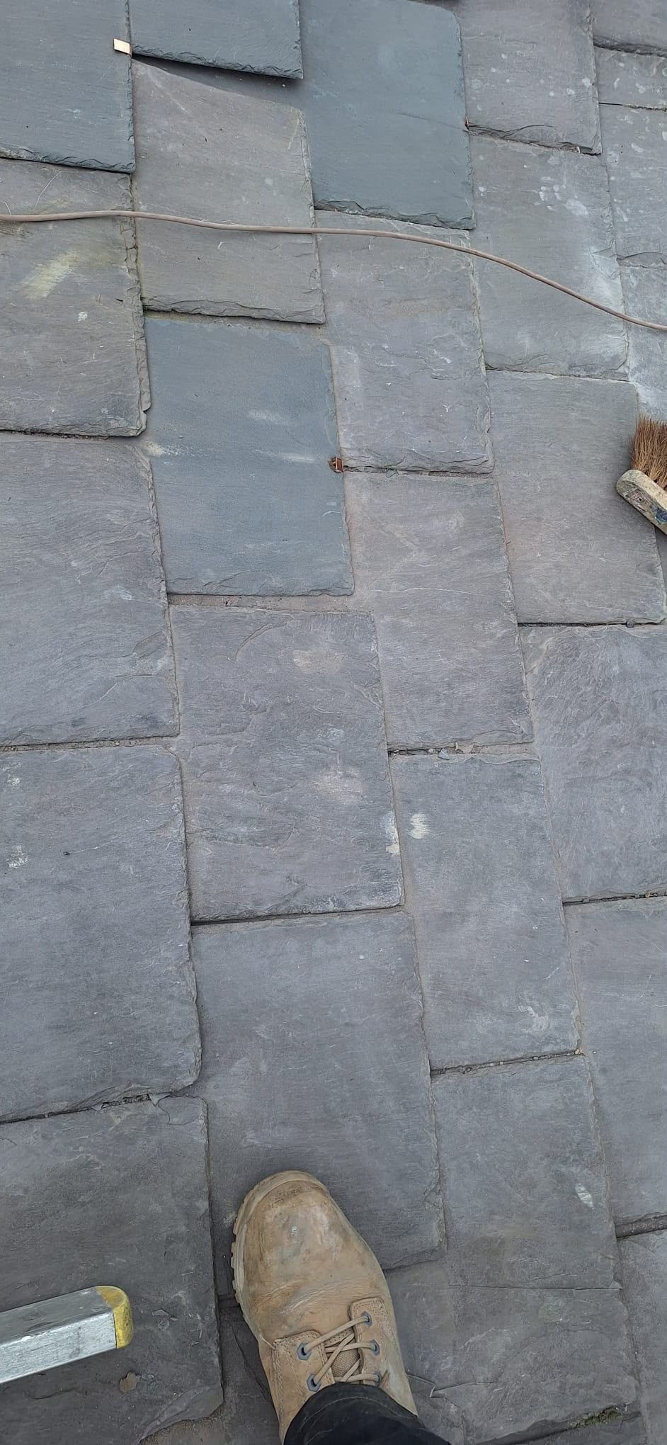 Close-up of gray roof slates with a boot visible at the bottom edge.
