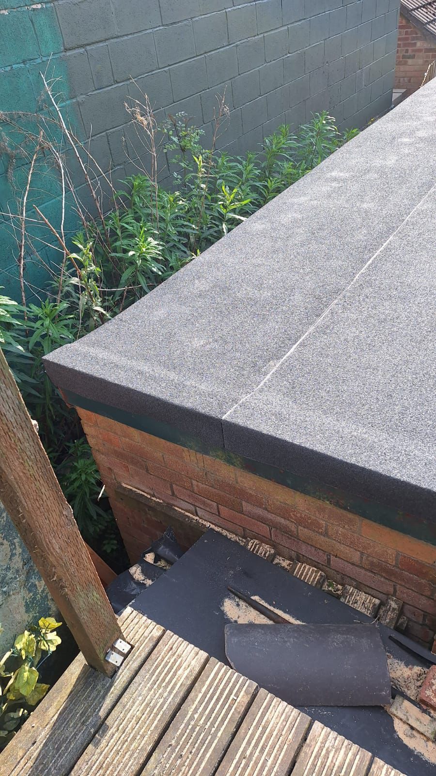 A close up of a wooden deck with a roof in the background.