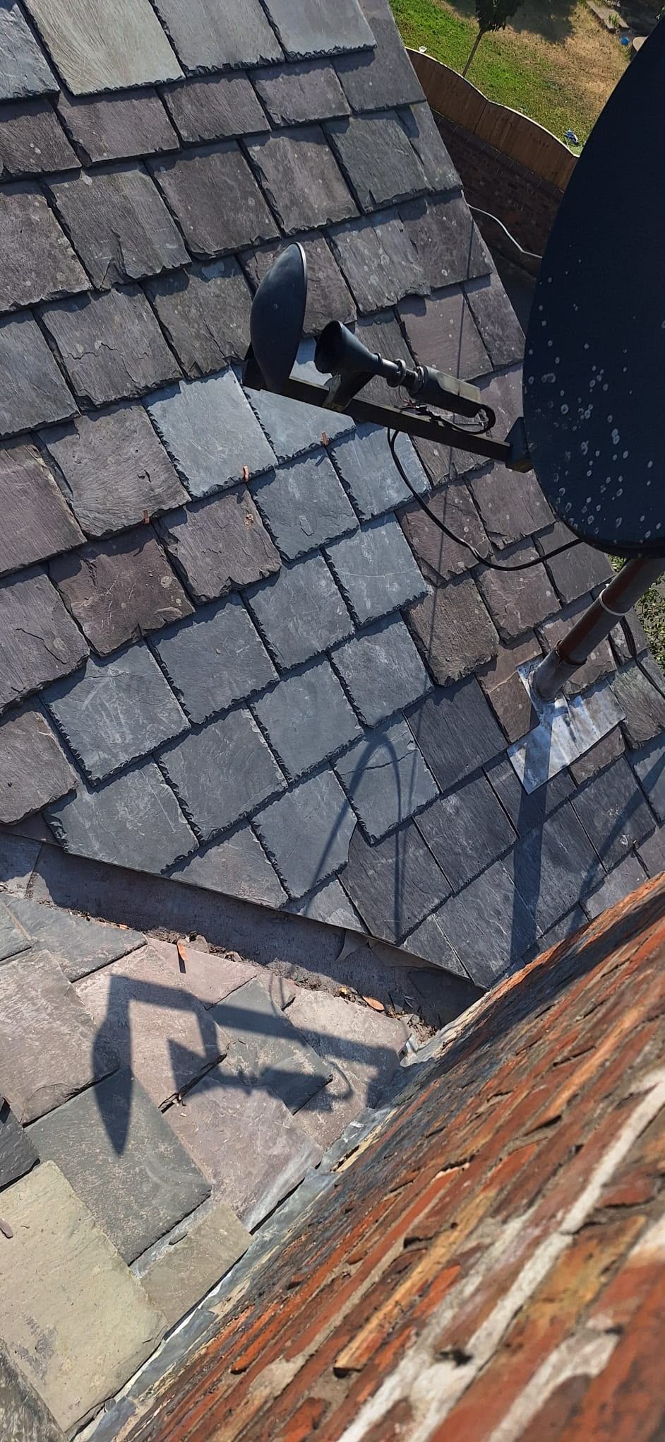 Roof shingles with a black vent pipe and a brick chimney in view