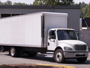 White box truck parked in front of a building.