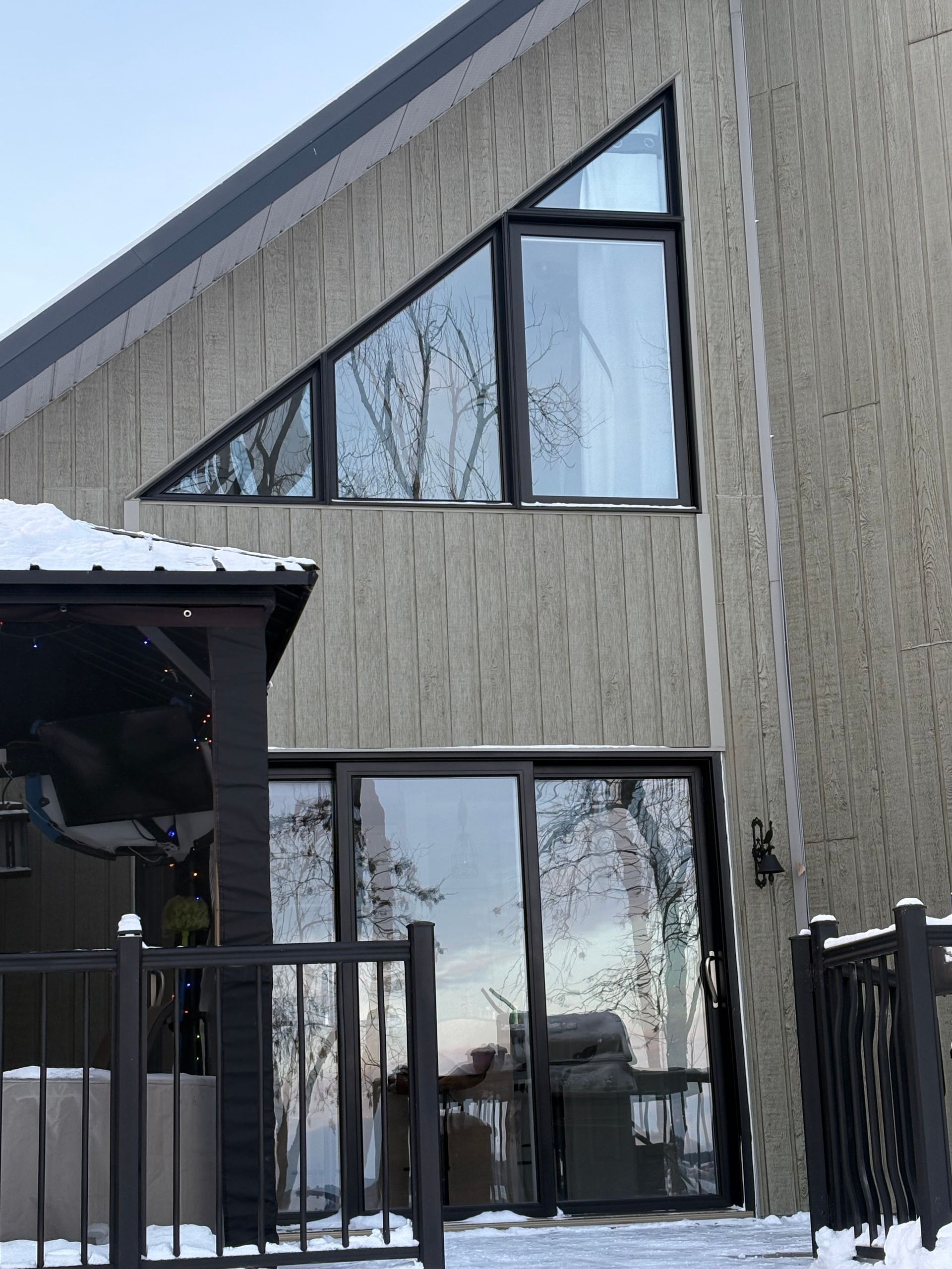 Extérieur du bâtiment avec fenêtre triangulaire et porte coulissante en verre, ambiance hivernale.