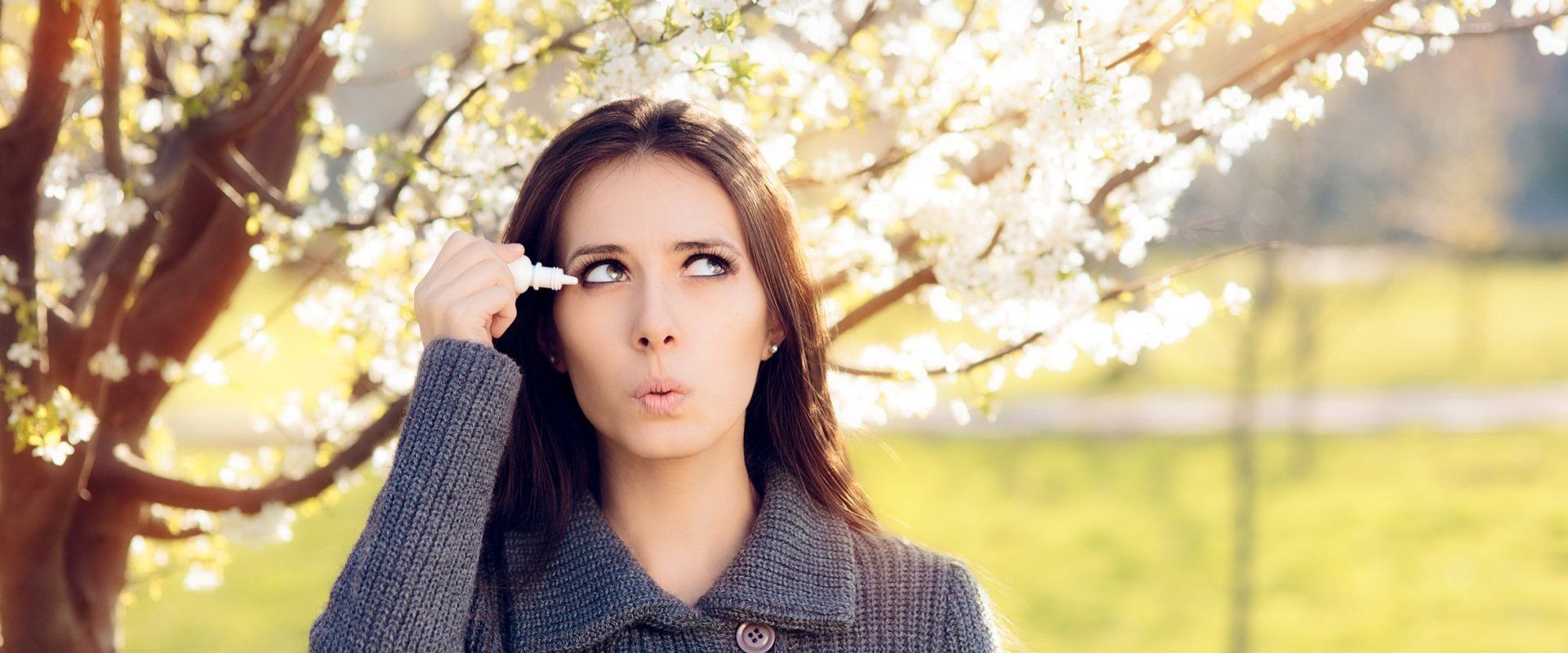 A woman putting eyedrops in her eye