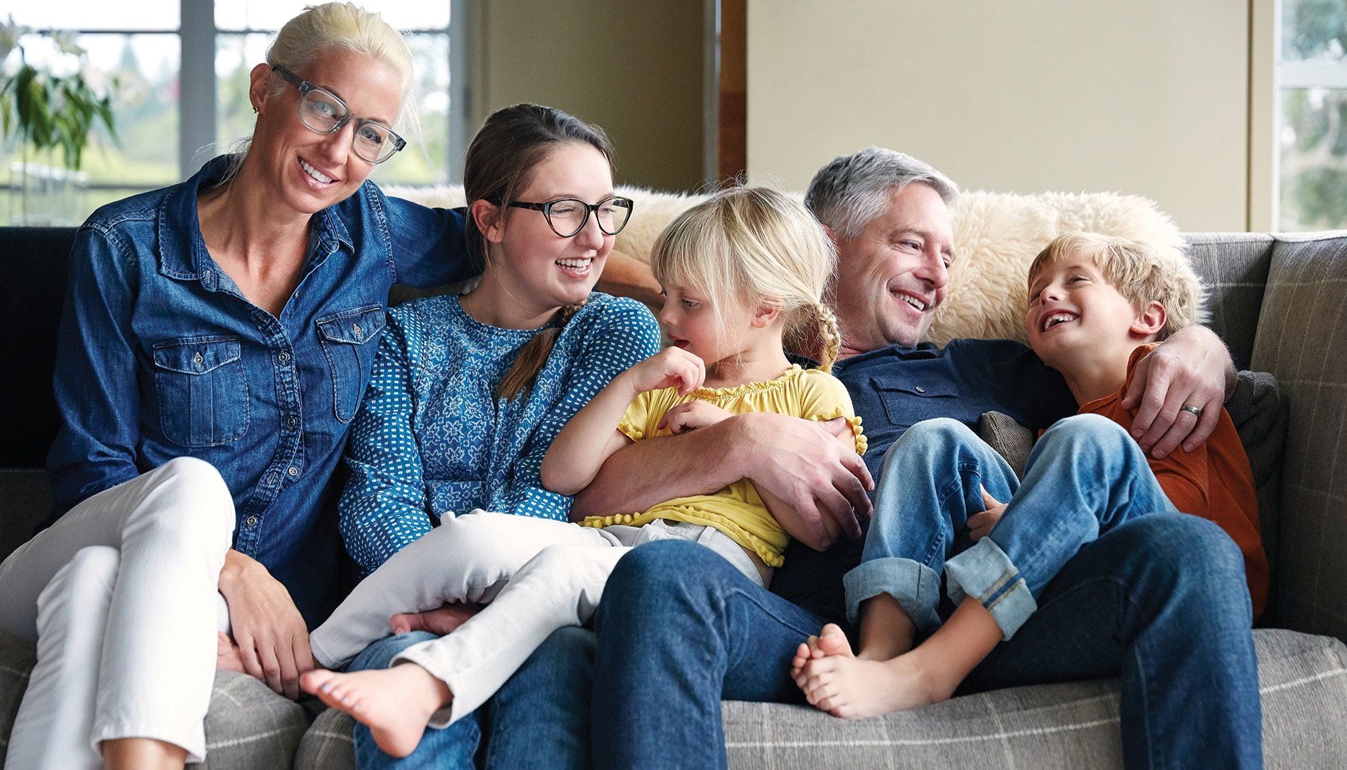A family is sitting on a couch together and smiling.