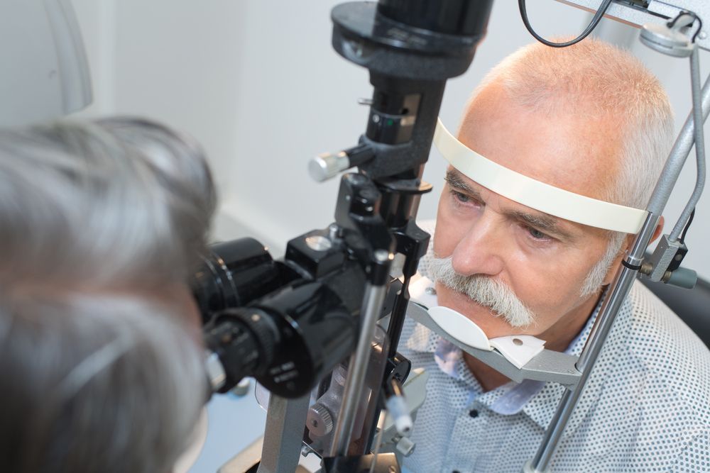 An older man is getting his eyes examined by an ophthalmologist.