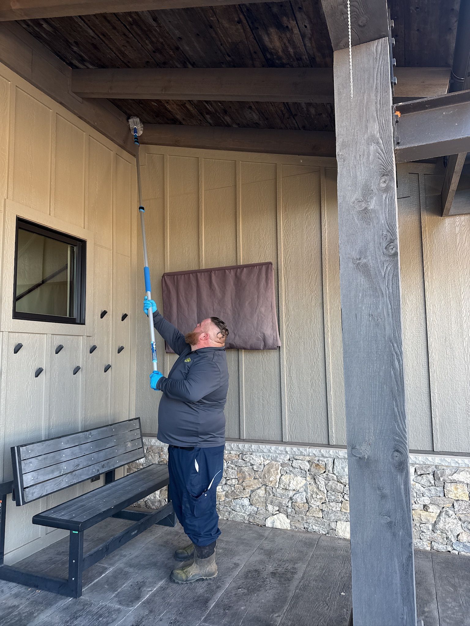 Man painting a building's ceiling with an extended roller; outdoor setting.