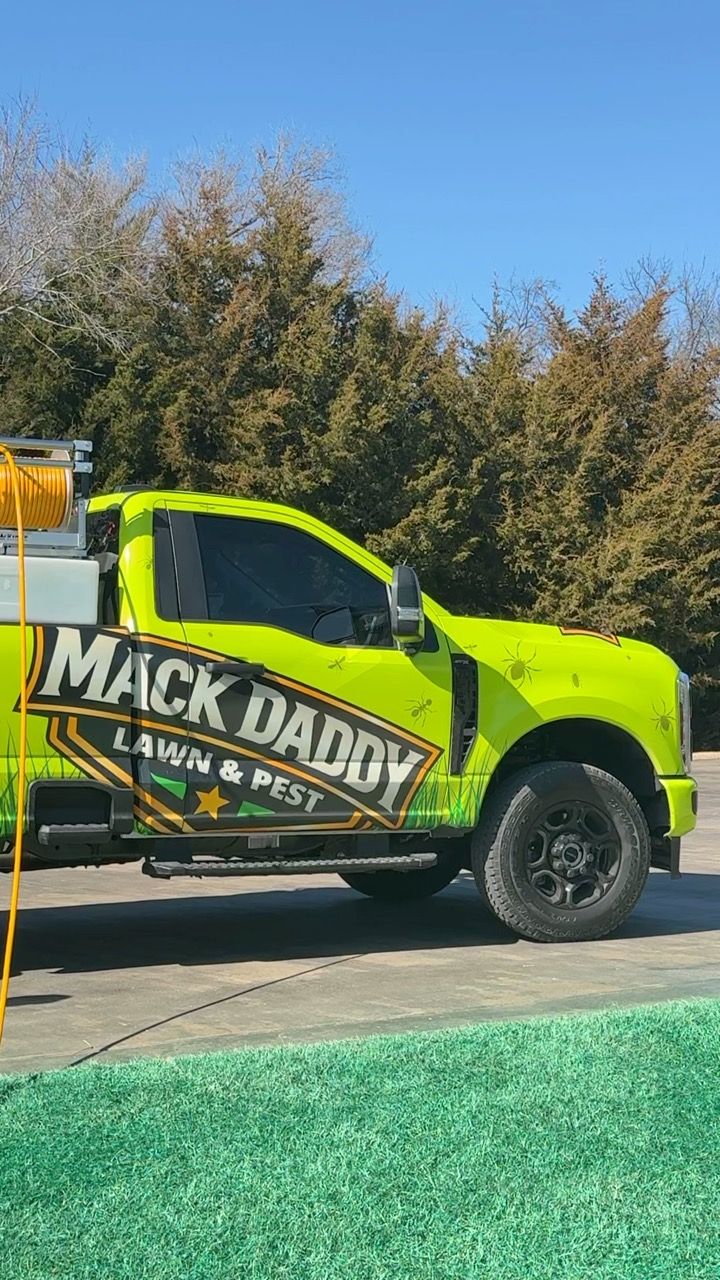 Bright green Mack Daddy Lawn & Pest truck parked outside with black wheels.