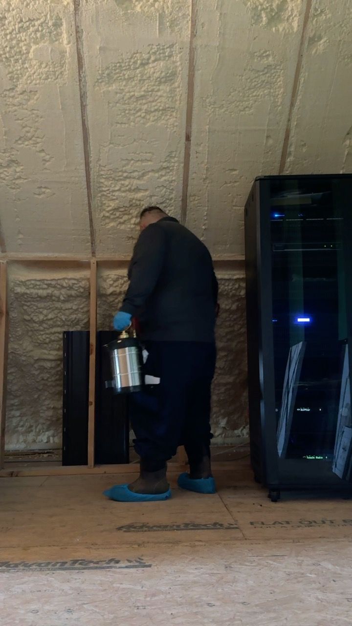 Person holding a canister inside a room with insulated walls. They wear blue shoe covers.