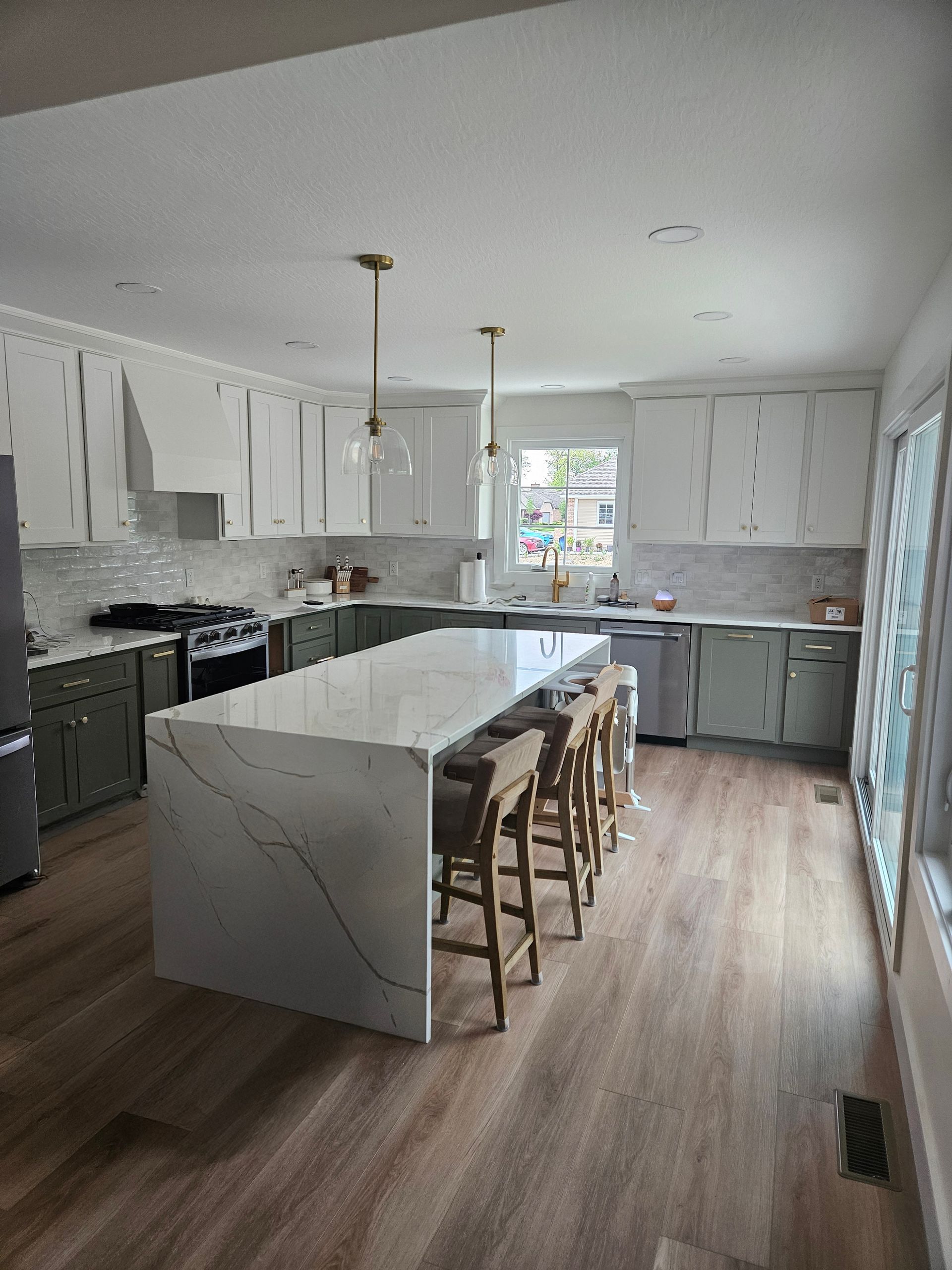 A kitchen with a large island in the middle and stools.