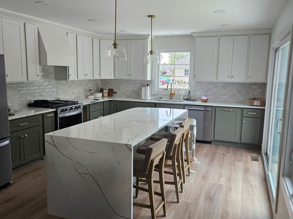 A kitchen with white cabinets and a large island in the middle.